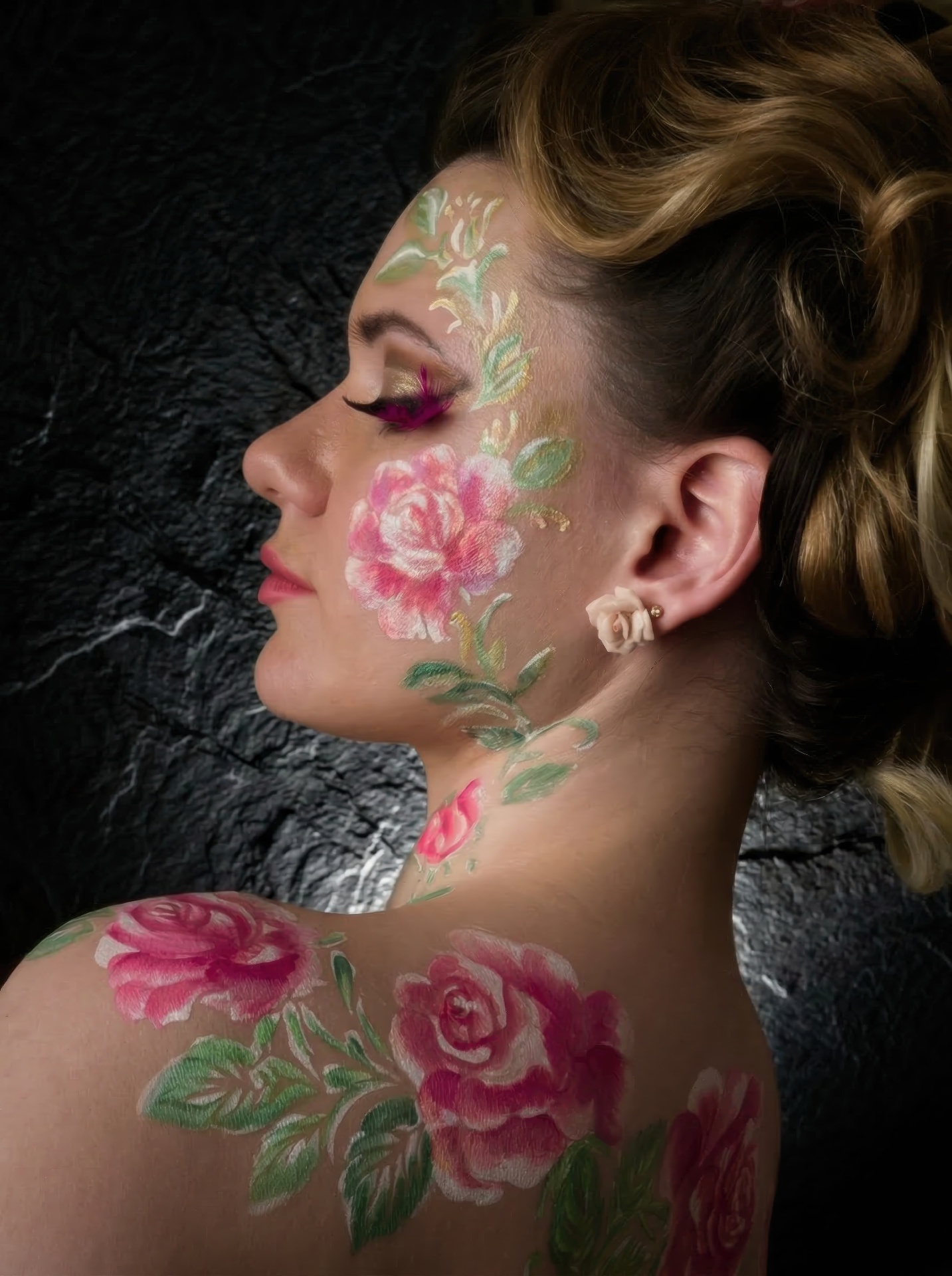 Close side profile of a woman with painted roses on her cheek and shoulder
