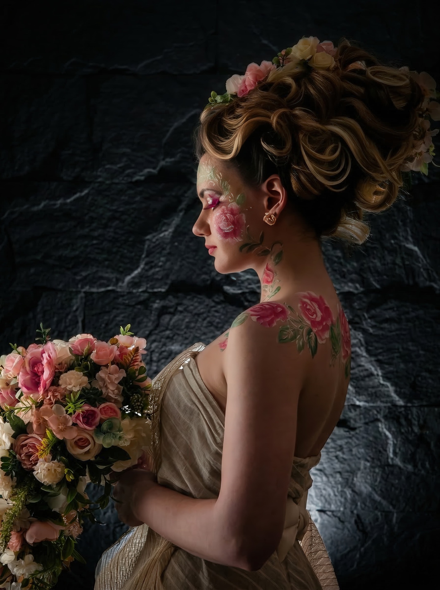 Woman with a floral updo seen from the side and behind, holding a bouquet