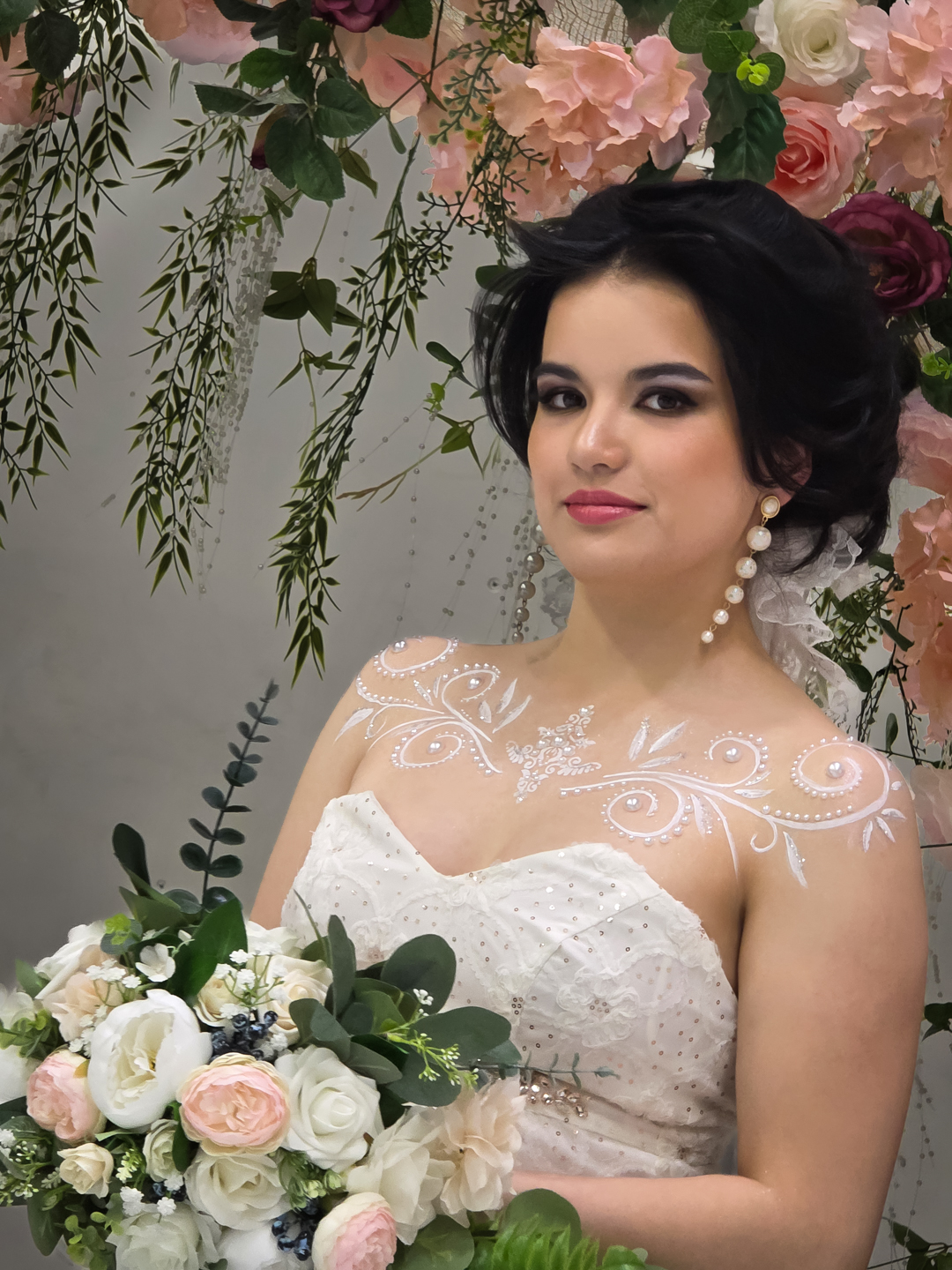 Bride in a white dress with a bouquet and a floral backdrop