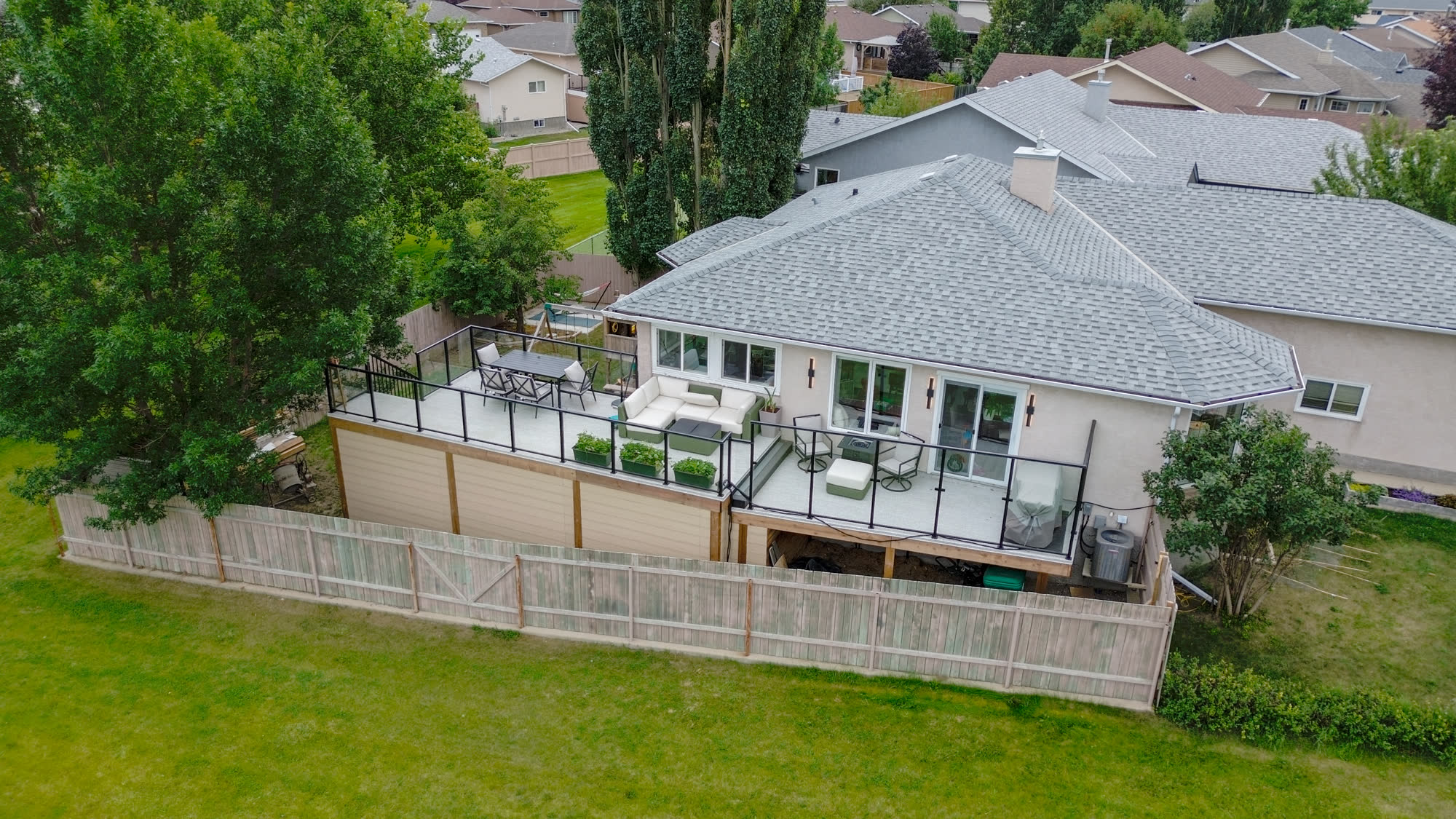 Aerial view of a raised deck with glass railings running along the back of the house
