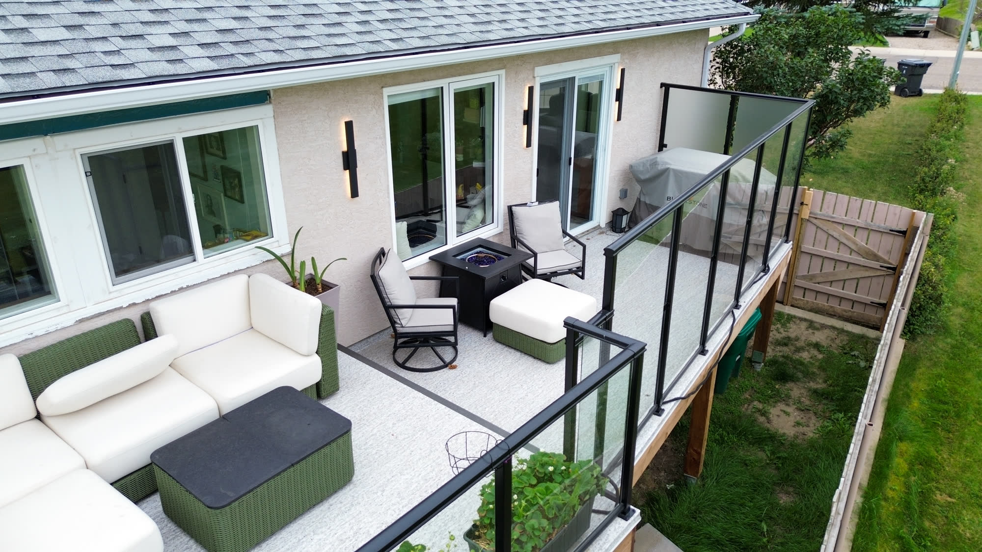 Aerial view of a raised deck with a fire table seating area and glass railings